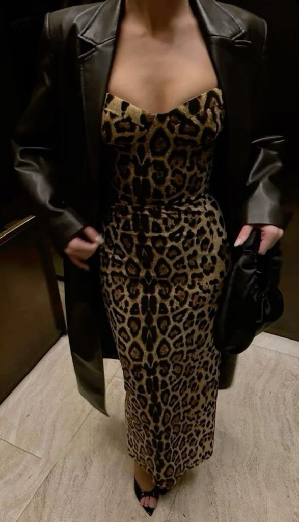 Lady putting on a leather jacket and a leopard skin dress